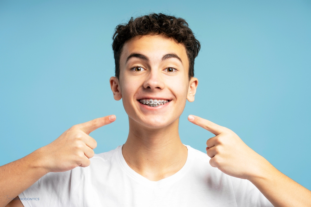 Excited teenage boy pointing at his metal braces with a big smile, highlighting braces cost in little falls, NJ.